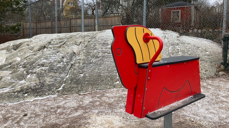 Gunghäst med klippa i bakgrunden.