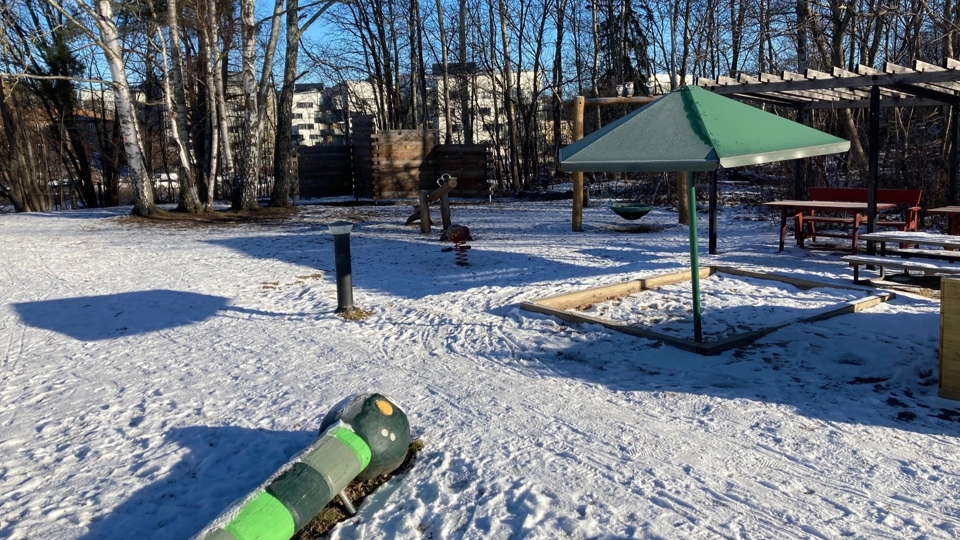 Lekplats med kompisgunga, sandlåda med solskydd och picknickbord.