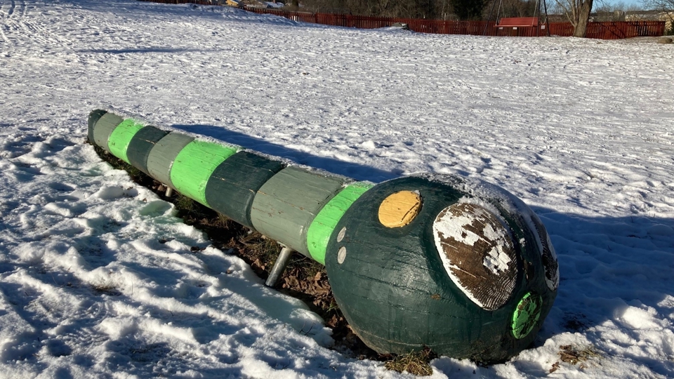Öppen gräsyta med ett lekdjur i trä.