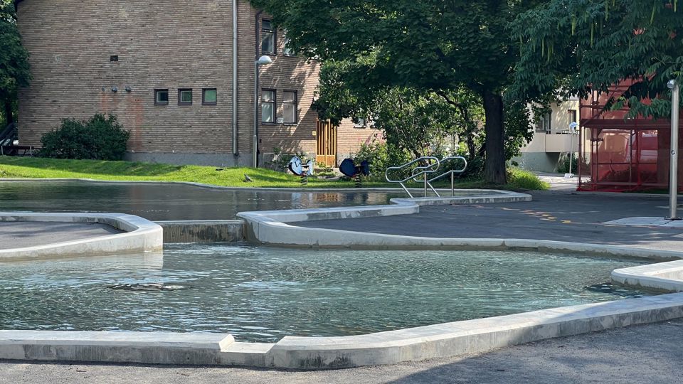 Plaskdamm med bostadshus i bakgrunden.