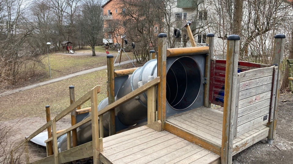 En lekplats med en rutschkana i form av ett långt rör.