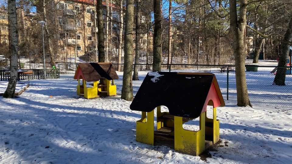 Lekplats med lekhus och flerfamiljshus i bakgrunden