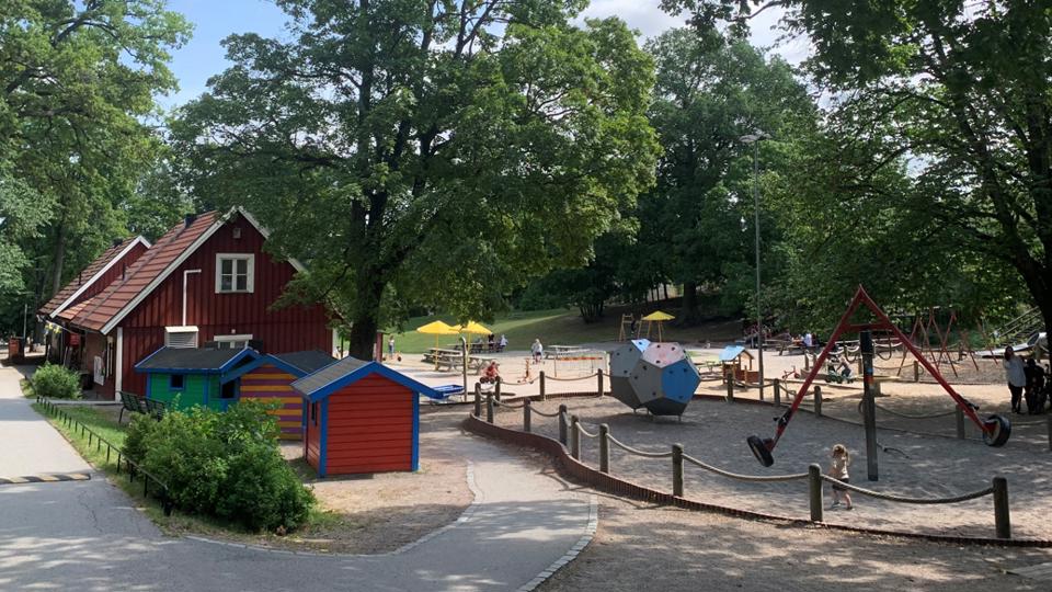 Grönskande vy över parklekshus, lekstugor och lekredskap.