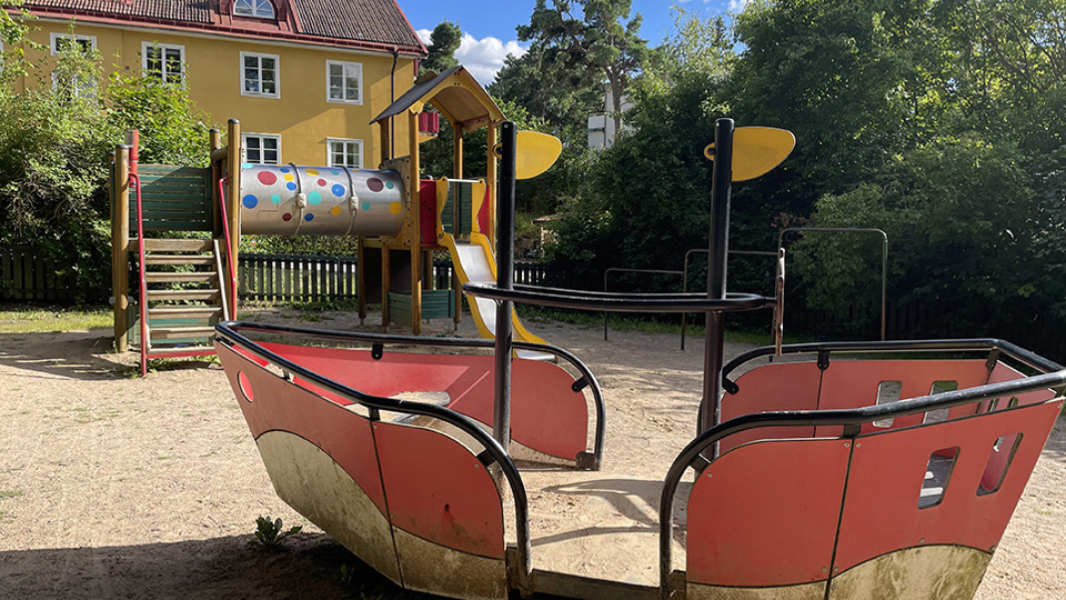 Lekplats med klätterställning, rutschkana och en båt.