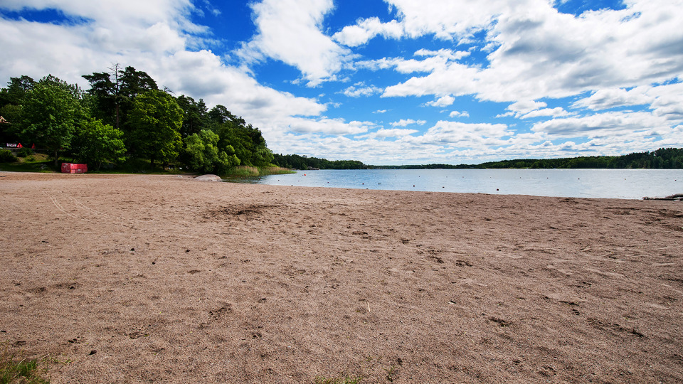 Sandstrand breder ut sig mot vattnet.