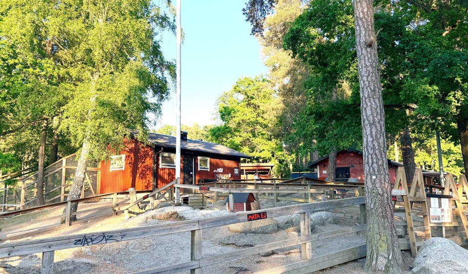 Flera röda små hus med djurinhägnader framför.