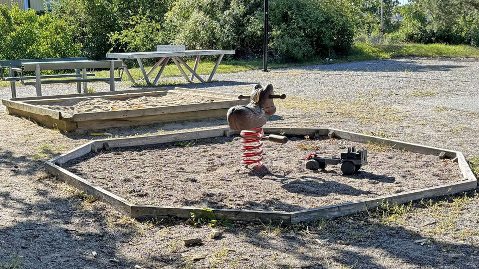 Lekplats med sandlåda och bänkar, foto.
