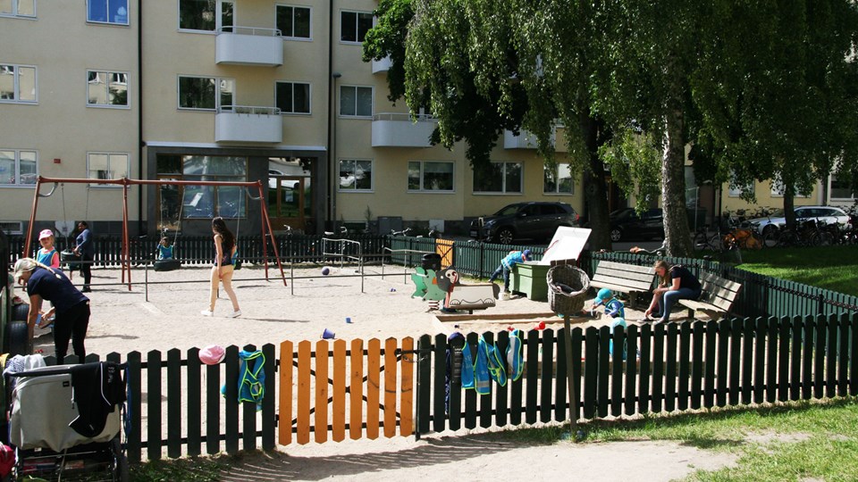 En liten lekplats omgärdad av ett grönt staket.