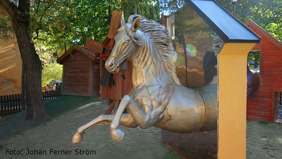 Fantasifull lekplats med en silverfärgad häst som hoppar ut ur en spegel.