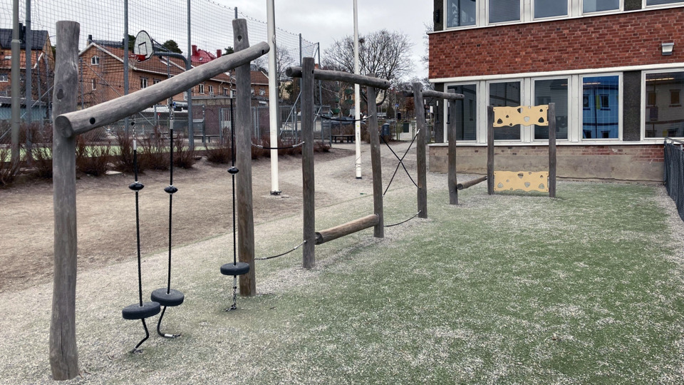 En klätterställning på en lekplats invid en skola.