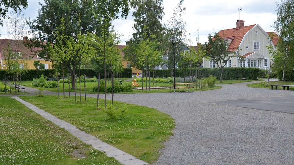 Den gröna lekparken med lekskulptur och villor i bakgrunden.